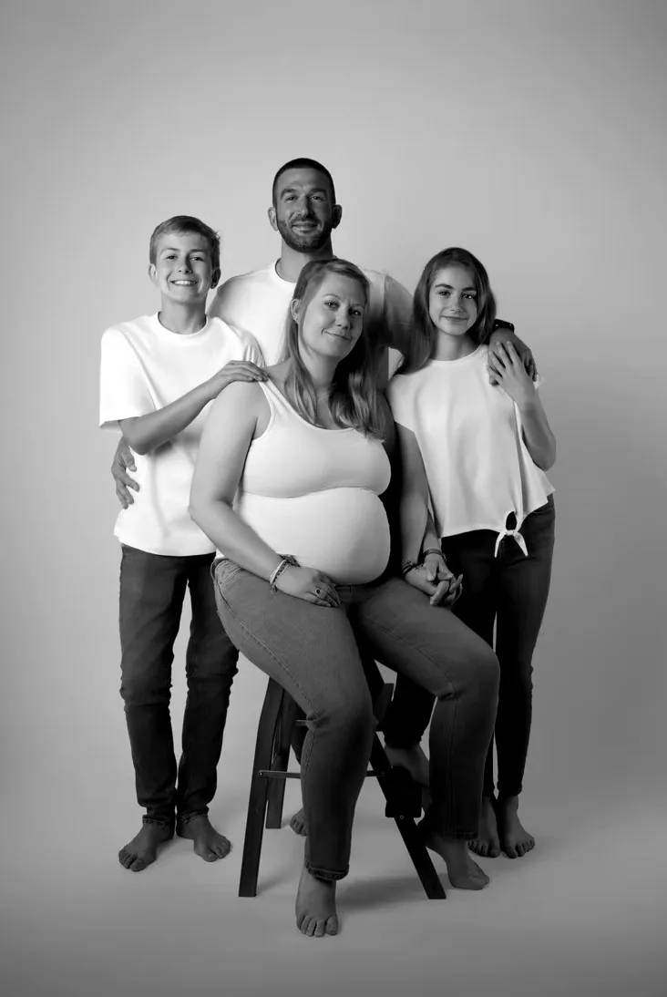 Une famille avec deux ados autour de la future maman assise sur un tabouret