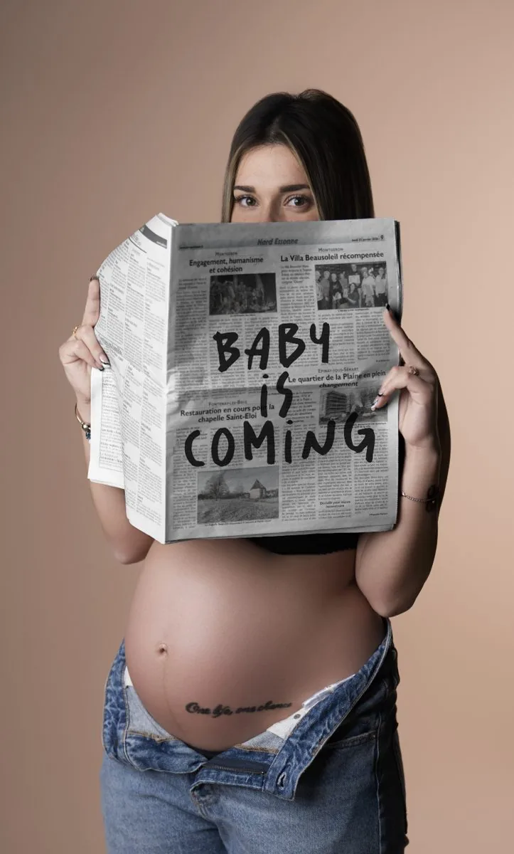 Future maman cachée derrière un journal « Baby is coming »