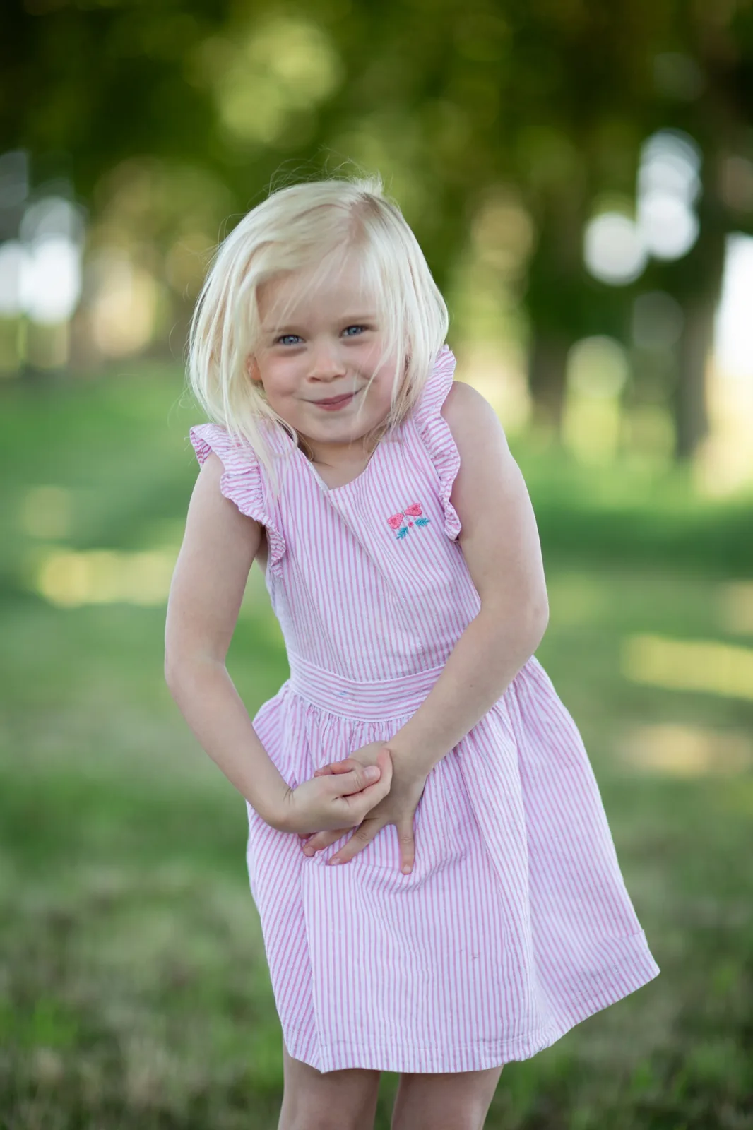 Fillette en robe rayée rose dans un parc