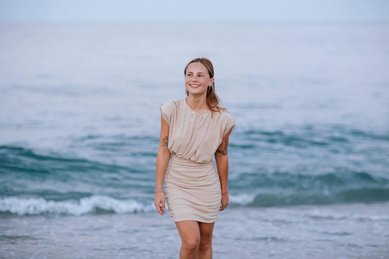 Jeune femme en robe beige au bord de la mer