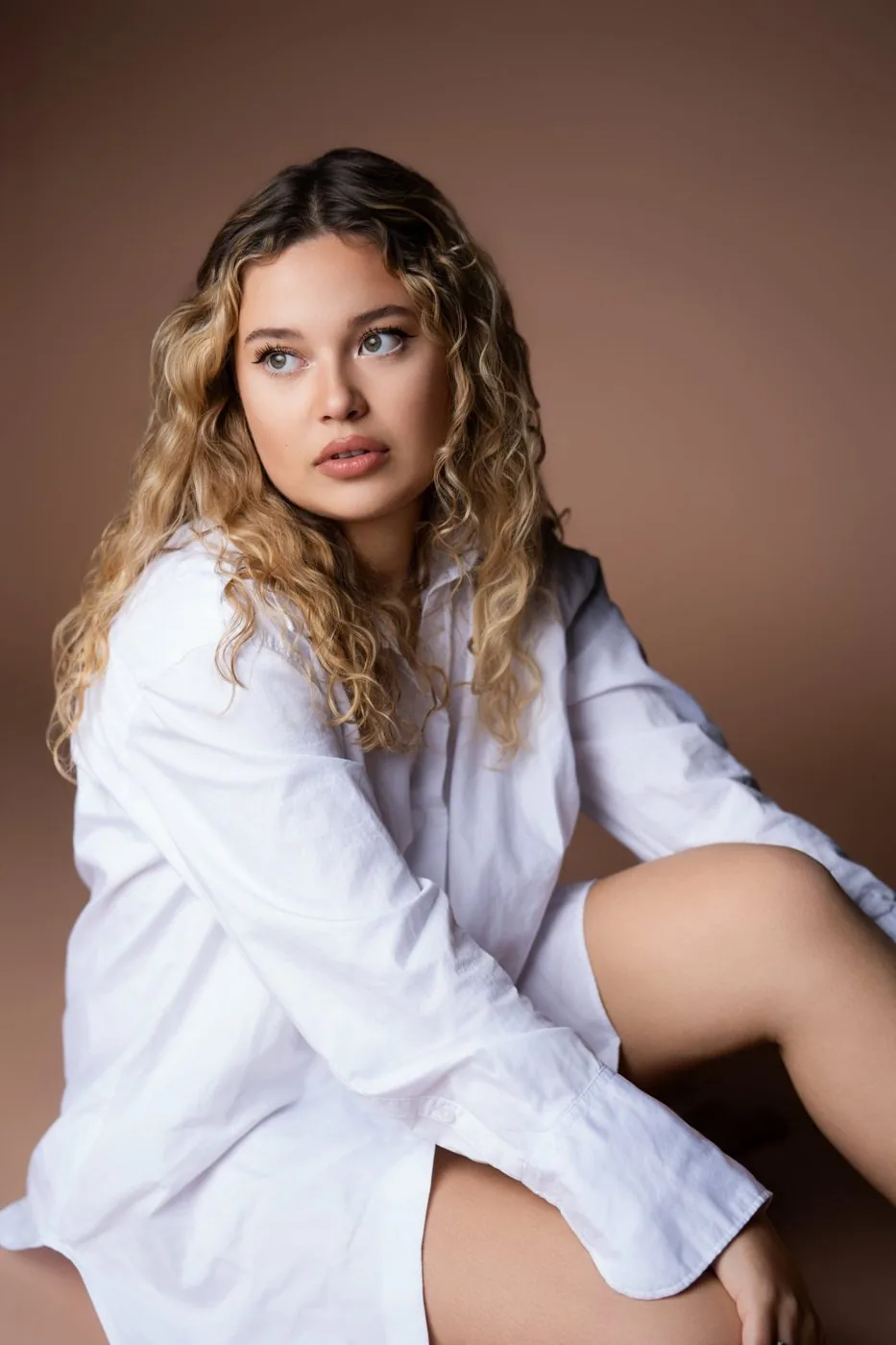 Portrait en chemise blanche, regard de côté, fond terracotta