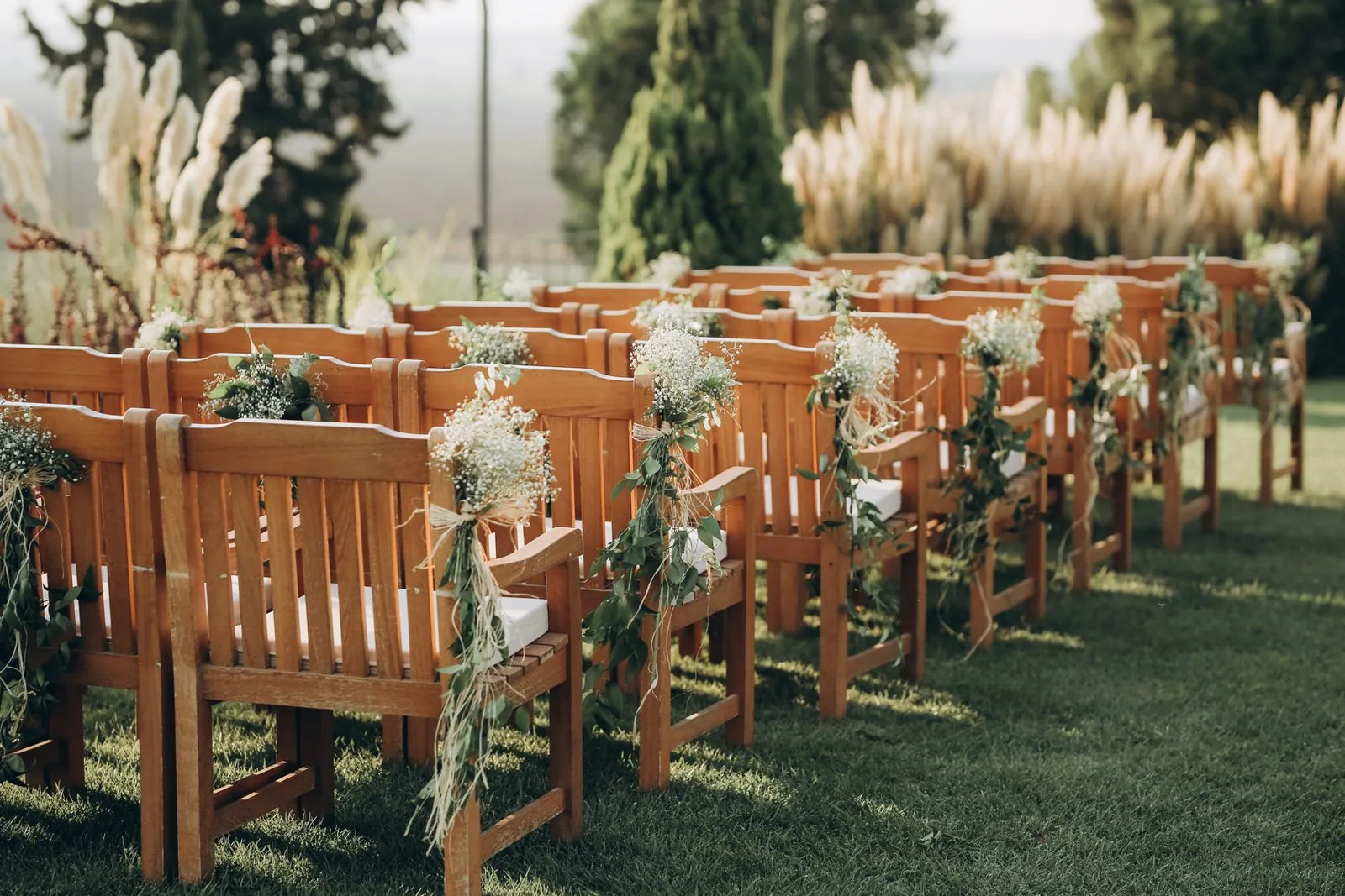 Chaises en bois décorées de pampas pour une cérémonie laïque en plein air
