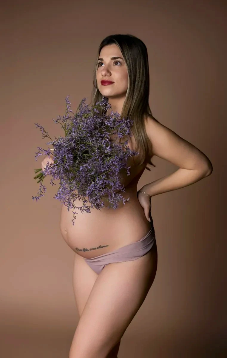 Future maman tenant un bouquet de fleurs violettes